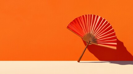 Poster - Elegance in Orange: A red hand fan poised elegantly, casting a striking shadow against a vibrant orange backdrop, symbolizing culture and design.