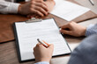 © New Africa - Client signing notarial document during meeting with lawyer at wooden table indoors, closeup