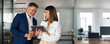 © Stock 4 You - Mature team of partners business man and European business woman discussing project on tablet standing in office. Two colleagues of professional business people working together. Banner, copy space