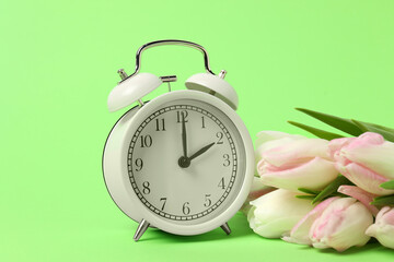 Poster - Spring time. Alarm clock and beautiful tulips on green background