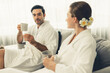 © InfiniteFlow - Beauty or body treatment spa salon vacation lifestyle concept with couple wearing bathrobe relaxing with drinks in luxurious hotel spa or resort room. Vacation and leisure relaxation. Quiescent