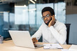 © Liubomir - A young professional contemplates at his desk in a modern office, with a laptop and documents beside him.