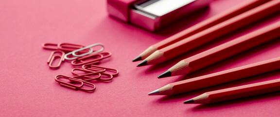 Poster - Red pencils and paper clips on pink background, showcasing stationery items.  Clean and simple design, ideal for office supplies or school themes