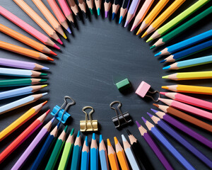 Poster - Colorful pencils arranged in a circle on dark gray surface, creating a frame with free space in center for text or logo, symbolizing creativity, art, and education