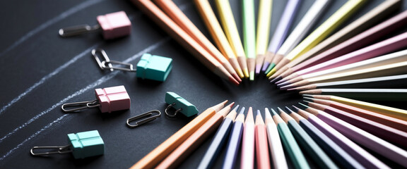 Aufkleber - Colored pencils arranged in two semicircles on dark surface, creating a heart shape.  Small gift-shaped paper clips scattered nearby. Represents creativity, artistry, and childhood