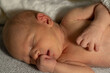 © Anat art - Newborn baby peacefully sleeping on a soft blanket with one hand near the face in a cozy environment at home