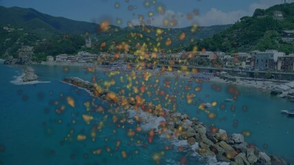 Poster - Colorful particles animation over coastal town with rocky shoreline and boats