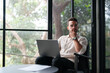 © Dorde - Young Male Professional Thinking in Modern Office with Laptop and Natural Light Background