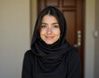 © Julija - In a cozy indoor setting, a young Muslim woman from Gaza elegantly wears a black scarf that complements her graceful smile, showcasing her cultural identity and inner strength Generative AI
