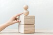 © gelas - Hand Balancing Wooden Blocks on Table.