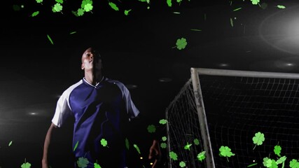 Poster - Soccer player heading ball with green clovers animation over dark background