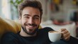 © Rakyandani - Smiling man enjoying a cup of coffee while relaxing on a cozy couch in a warm, inviting living room