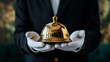 © Mmmdrza - A well-dressed butler in a dark suit and white gloves holding a brass bell, signifying the service industry and professional hospitality