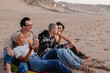 © PintoArt - Friends eating donuts at the beach during sunset