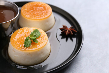 Wall Mural - tasty puddings with caramel sauce served on light grey table, closeup. space for text