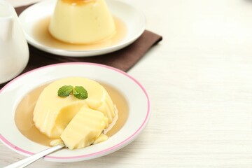 Wall Mural - delicious pudding with caramel sauce and mint served on white table. space for text