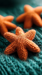 Aufkleber - Close-up of orange knitted starfish on teal knitted fabric.  Texture focus, showcasing warmth and craft. Ideal for cozy or handmade themes.