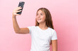 © luismolinero - Little caucasian girl isolated on pink background making a selfie