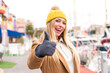 © luismolinero - Young pretty blonde woman wearing winter jacket at outdoors with thumbs up because something good has happened