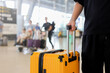 © chinnarach - close up young traveler man hand hold luggage and walk in side of airport terminal to go to gate for boarding to abroad with international flight for travel insurance and holiday lifestyle concept