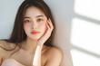 © Sunny Good Cat - beautiful young woman with long hair is sitting gracefully against light background, showcasing serene expression. soft lighting highlights her features, creating calm and inviting atmosphere