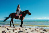 Young asian woman ride on horse on lake shore on summer day
