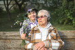 © leksann - Happy grandson hugs old great-grandmother in fashionable clothes. Boy gives flowers to great-grandmother. Family group, support, help, connection of generations.