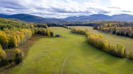 Poster - Expansive Aerial View of a Vibrant Green Field Surrounded by Beautiful Mountains and Clouds : Generative AI