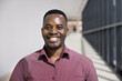 © fizkes - Head shot portrait of satisfied African businessman, corporate staff member looking at camera, posing standing in modern office hallway, exuding competence and success. Company boss, profile picture