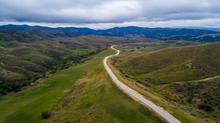 Aufkleber - Aerial View of Winding Road Through Scenic Green Hills and Mountains Under Cloudy Sky : Generative AI