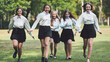 © Довидович Михаил - Five joyful students wearing lilac bow ties running together in a park, having a great time after school on a sunny day