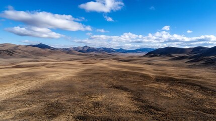 Aufkleber - Breathtaking Aerial Landscape of a Vast Brown Plain with Rolling Hills and Distant Mountains Under Blue Skies : Generative AI