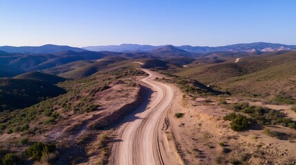 Poster - Winding dirt road leading through rolling green hills under clear blue sky : Generative AI