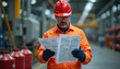 © miss irine - Worker in orange uniform wearing red hard hat reviews Safety Data Sheets in warehouse. Industrial workplace with chemical containers. Job safety, hazard communication, chemical safety, worker