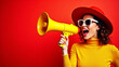 © Vishwesh - Stylish brunette woman shouting in megaphone about final sales and Black Friday discounts on red background