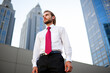 © Minerva Studio - Businessman standing in the financial district looking up at skyscrapers