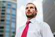 © Minerva Studio - Businessman looking up at the sky in the financial district