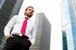© Minerva Studio - Confident businessman standing in the financial district looking up at skyscrapers
