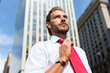 © Minerva Studio - Businessman adjusting his tie in front of skyscrapers