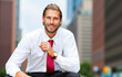© Minerva Studio - Portrait of smiling businessman adjusting his tie in city