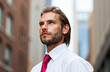 © Minerva Studio - Businessman looking up at skyscrapers in downtown Manhattan
