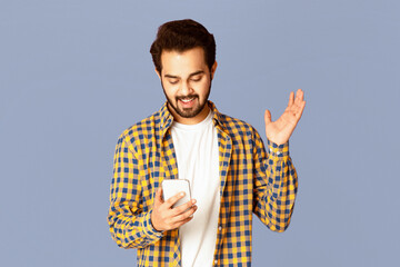 Poster - Excited Indian guy looking at smartphone in his hands on violet background, panorama