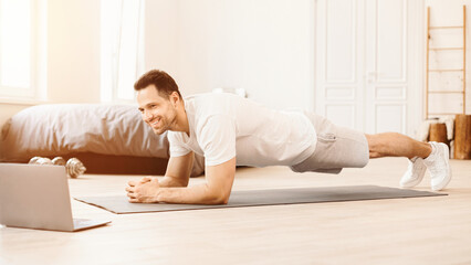 Aufkleber - Online Workout. Happy Guy Doing Plank Exercise At Laptop Computer Training On Floor At Home. Panorama