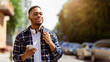 © Prostock-studio - Urban Lifestyle. Handsome black man holding cell phone, walking down the street, banner, copy space, selective focus