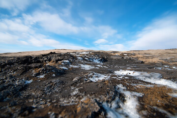 Poster - barren landscape with rocky terrain and patches of snow under bright blue sky