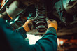 © MVProductions - Auto car repair service center. Mechanic examining car suspension