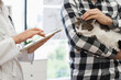 © sofiko14 - Veterinarian using tablet to explain medical history or prescription to man holding cat. Image shows assistance, animal care, and interaction with advanced technology