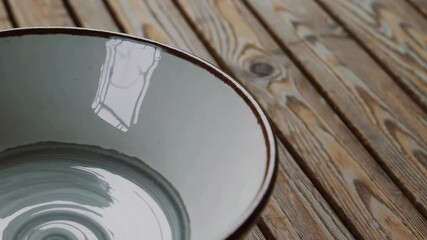 Poster - Ceramic bowl reflection on wooden surface showing light and shadow play