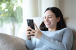 © Antonioguillem - Happy asian woman is using smart phone at home