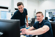 © Westend61 - Smiling male engineer showing computer to colleague in factory office